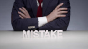 Business professional with arms crossed, with the word 'MISTAKE' in front, symbolizing the common legal mistakes that early-stage companies often make.