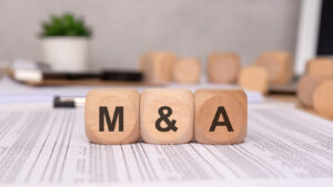 Wooden blocks with M & A letters on financial documents symbolizing Mergers and Acquisitions. Conceptual image representing the complexities and risks when mergers and acquisitions go wrong.