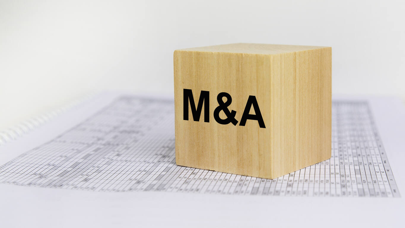 Wooden block with 'M&A' on it, symbolizing the importance of structuring mergers and acquisitions (M&A) transactions to minimize post-closing disputes.