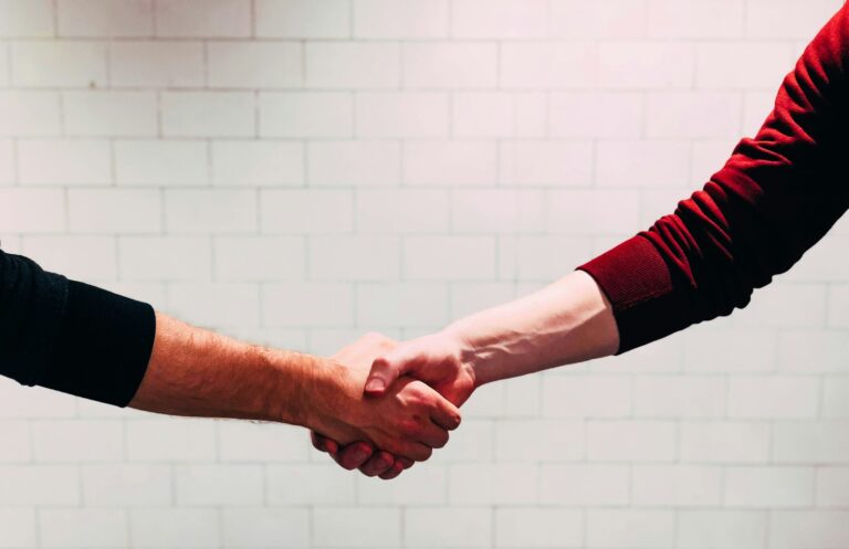 Two professionals shaking hands over an employment agreement in California